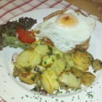 Fleischkäse unter Spiegelei neben Bratkartoffeln